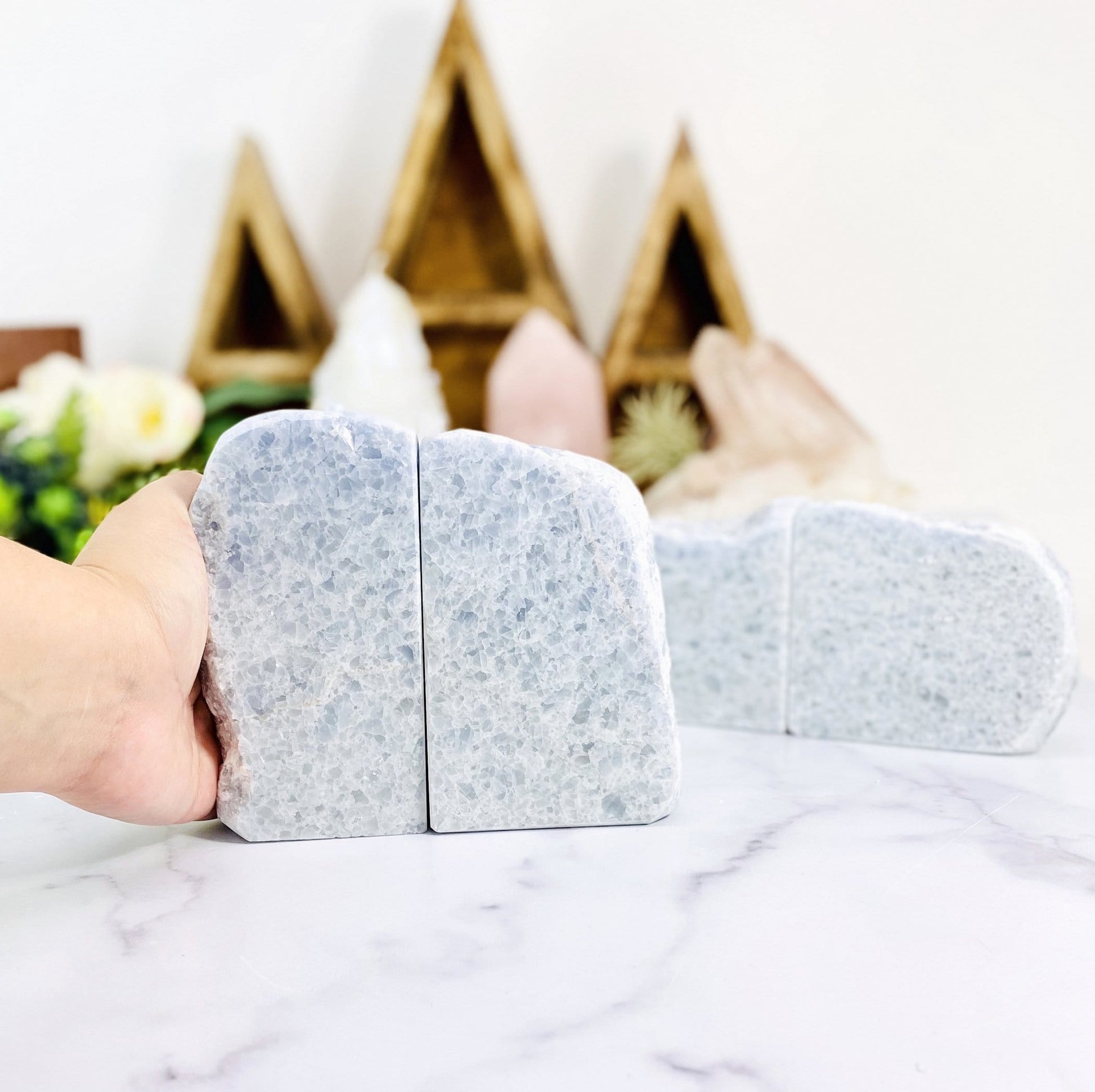 hand holding blue calcite bookends with other crystals blurred in the background