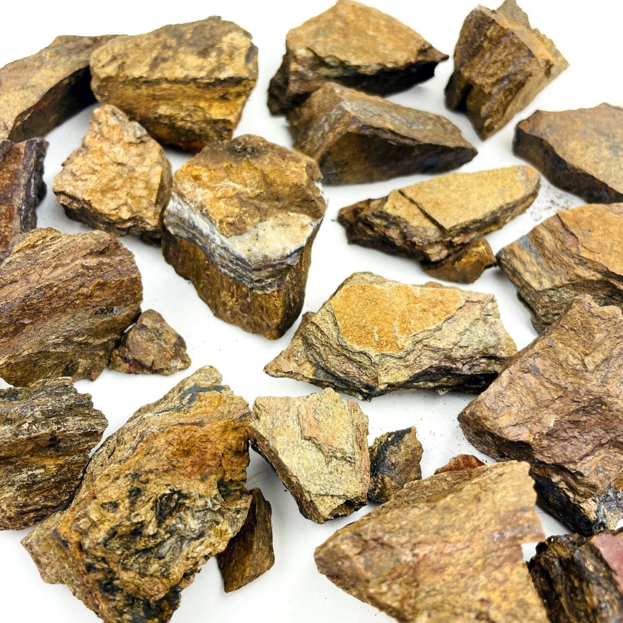 Tigers Eye Rough stones laid out on a table shown from a side view