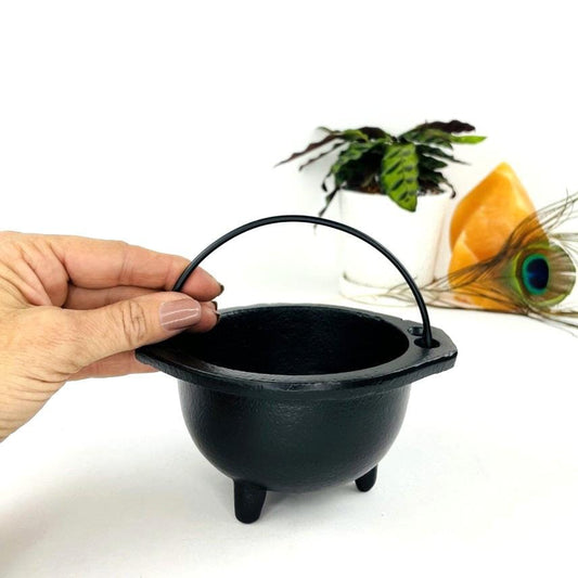 Hand holding the handle of the Black Cauldron