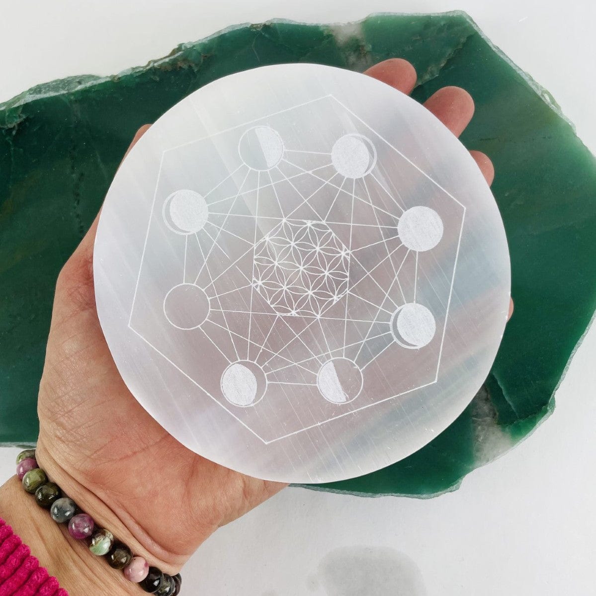 selenite moon phase engraved charging plate in hand for size reference
