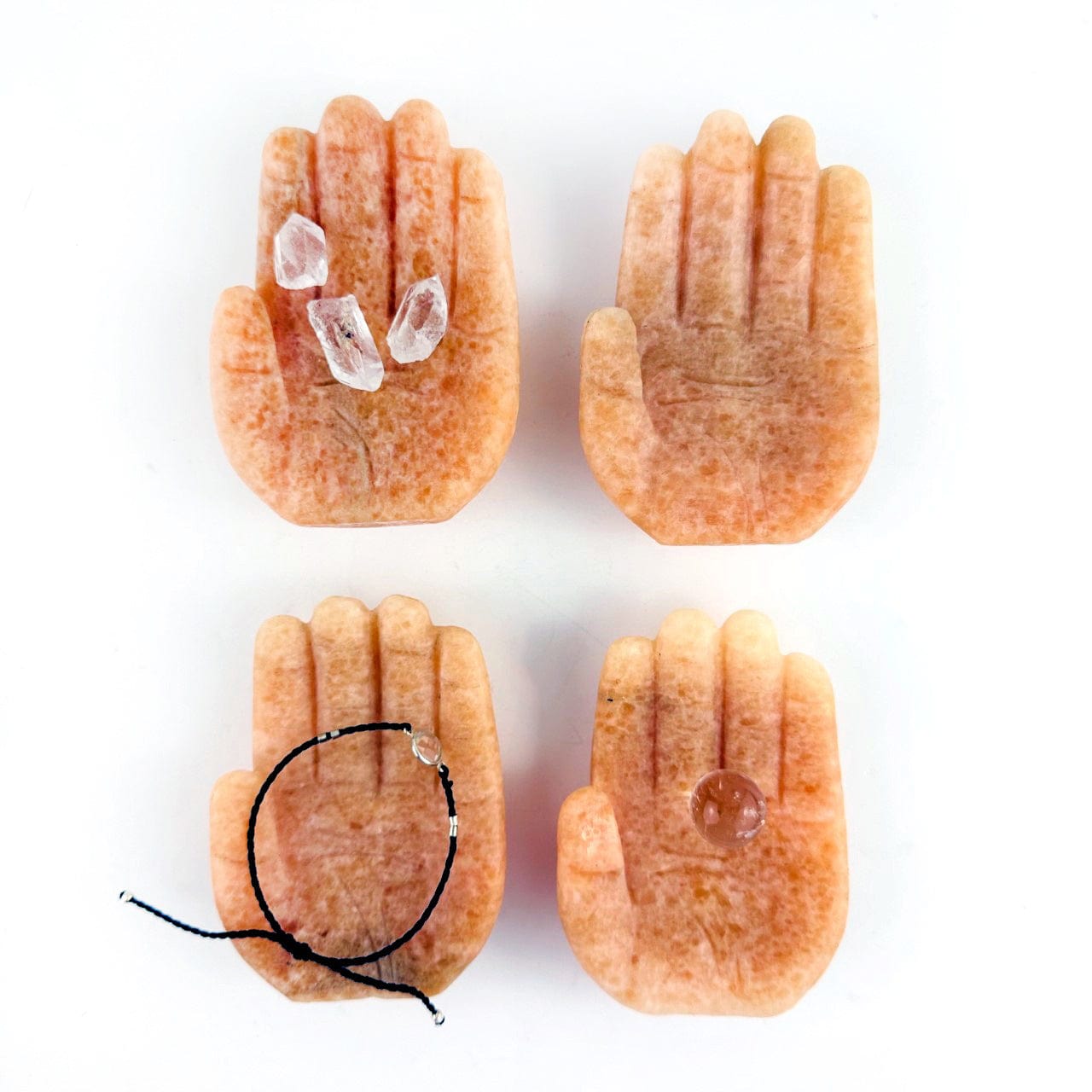 Hamsa Hand Stone Carvings in orchid calcite, shown with crystals in one, a small sphere in one and a bracelet in one