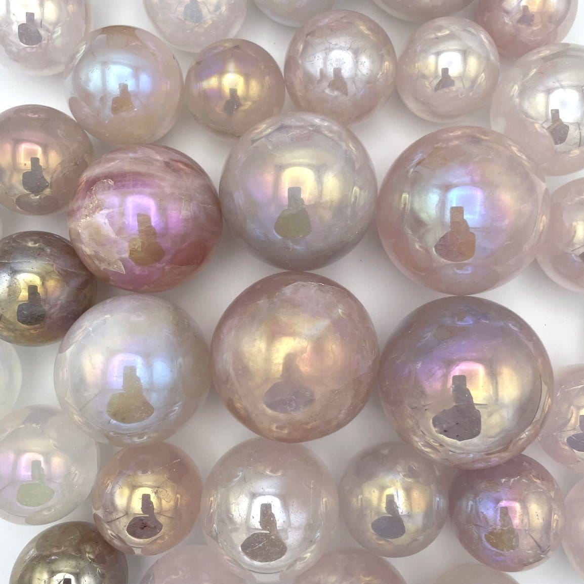 Group of Rose Quartz Angel Aura Titanium Spheres on white background