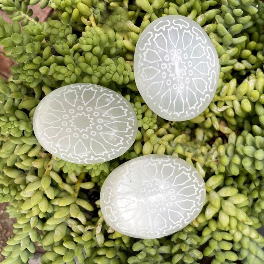 overhead view of selenite mandala engraved palm stones on display for possible variations