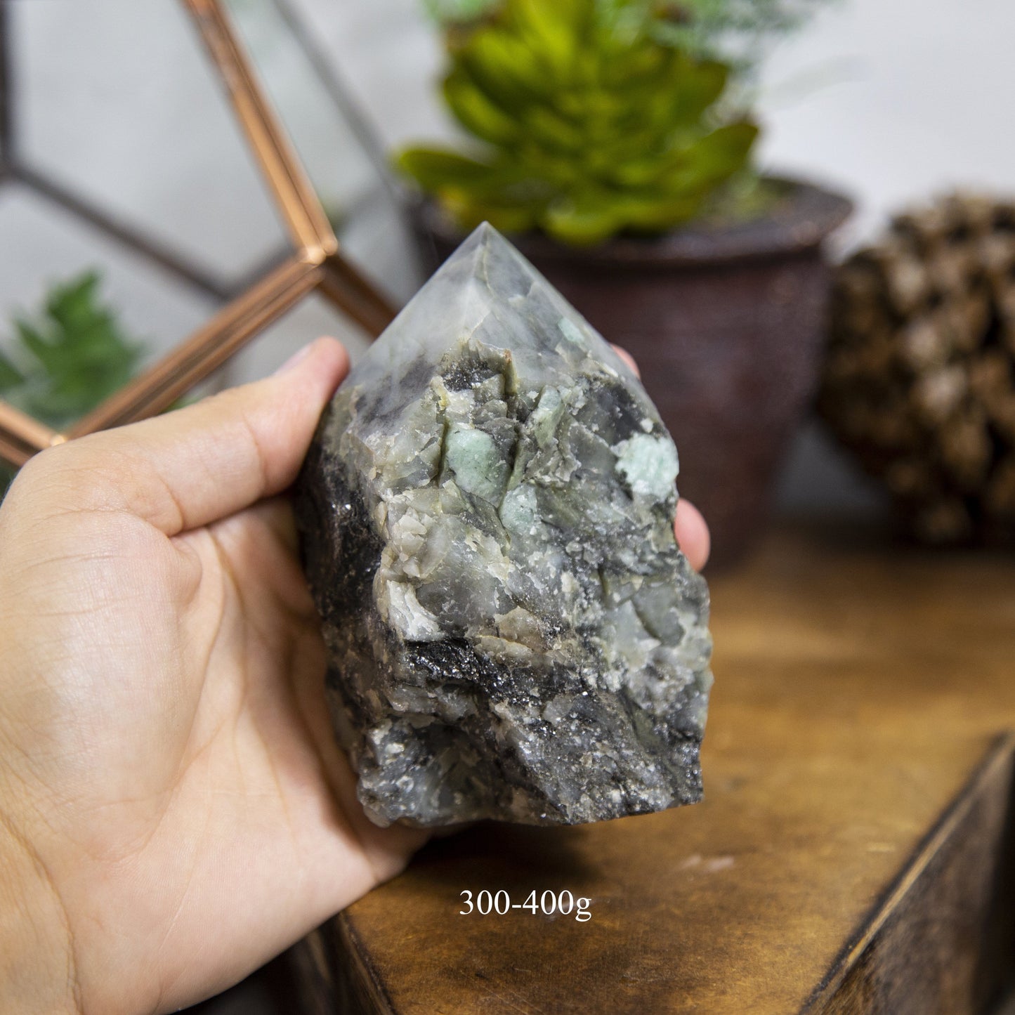 Semi Polished point Emerald Stone in hand showing the weight of 300 to 400g on white background