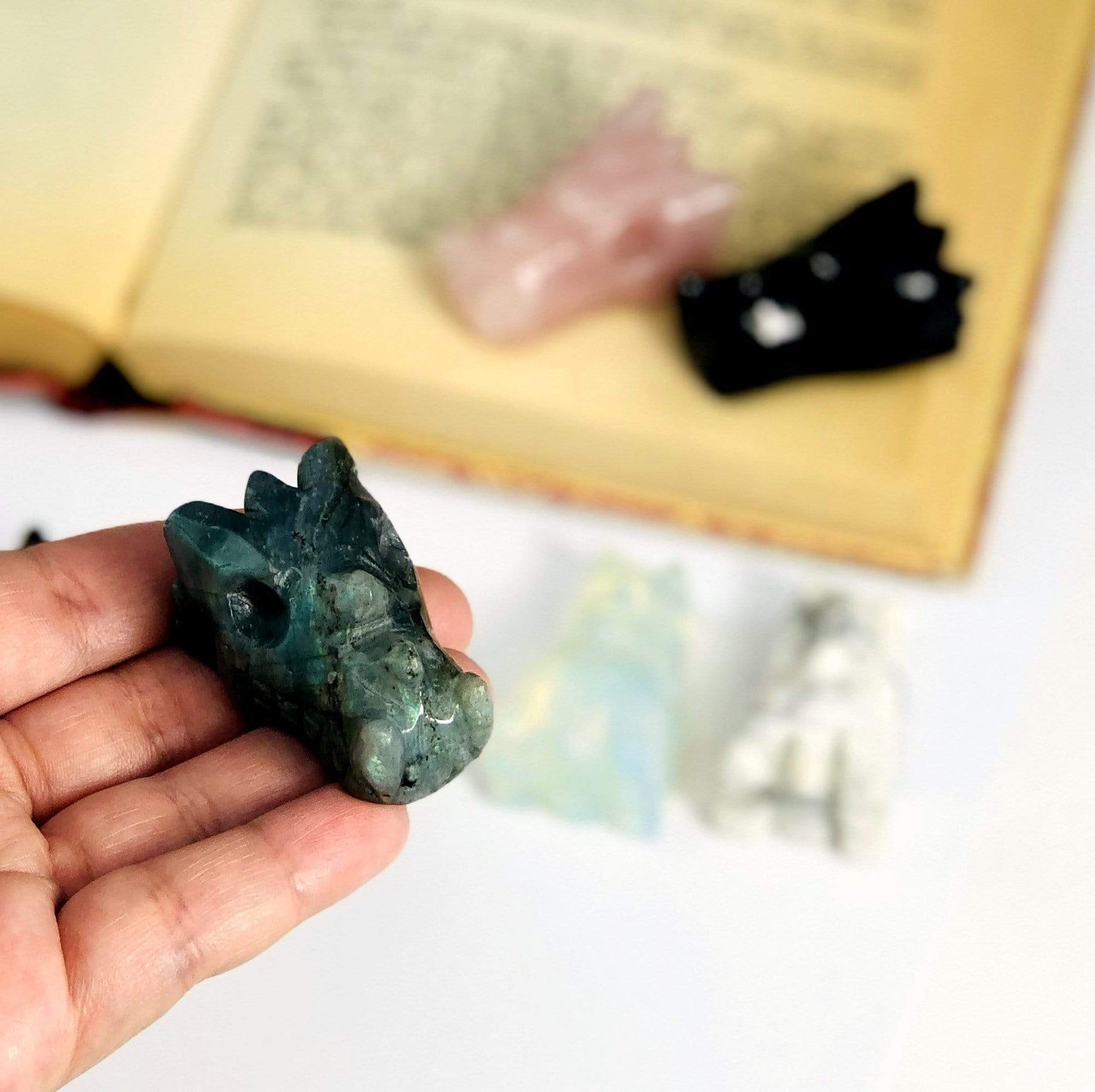 Labradorite Dragon Head Mini Statue in Hand on White Background.