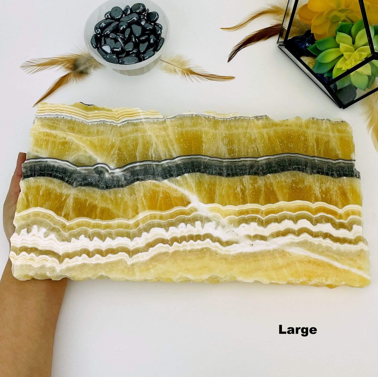 hand holding up large Mexican onyx platter with decorations in the background