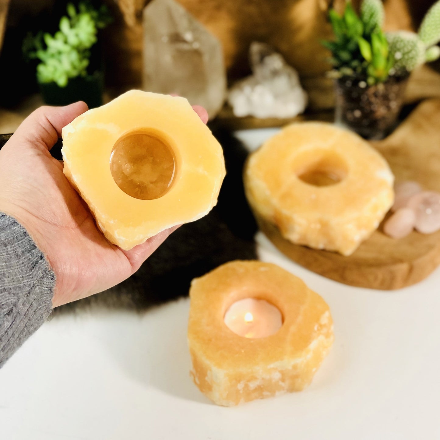 Hand holding up rough stone candle holder with 2 others in the background with decorations