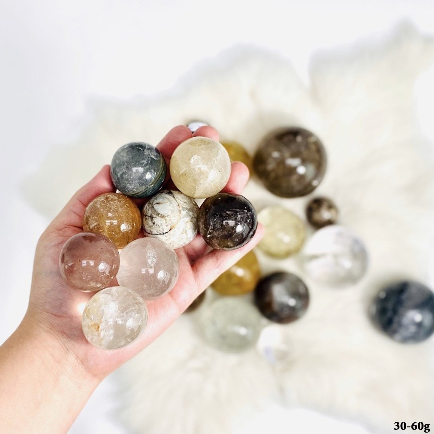 Assorted Crystal Quartz Spheres, between 30-60g, displayed in hand