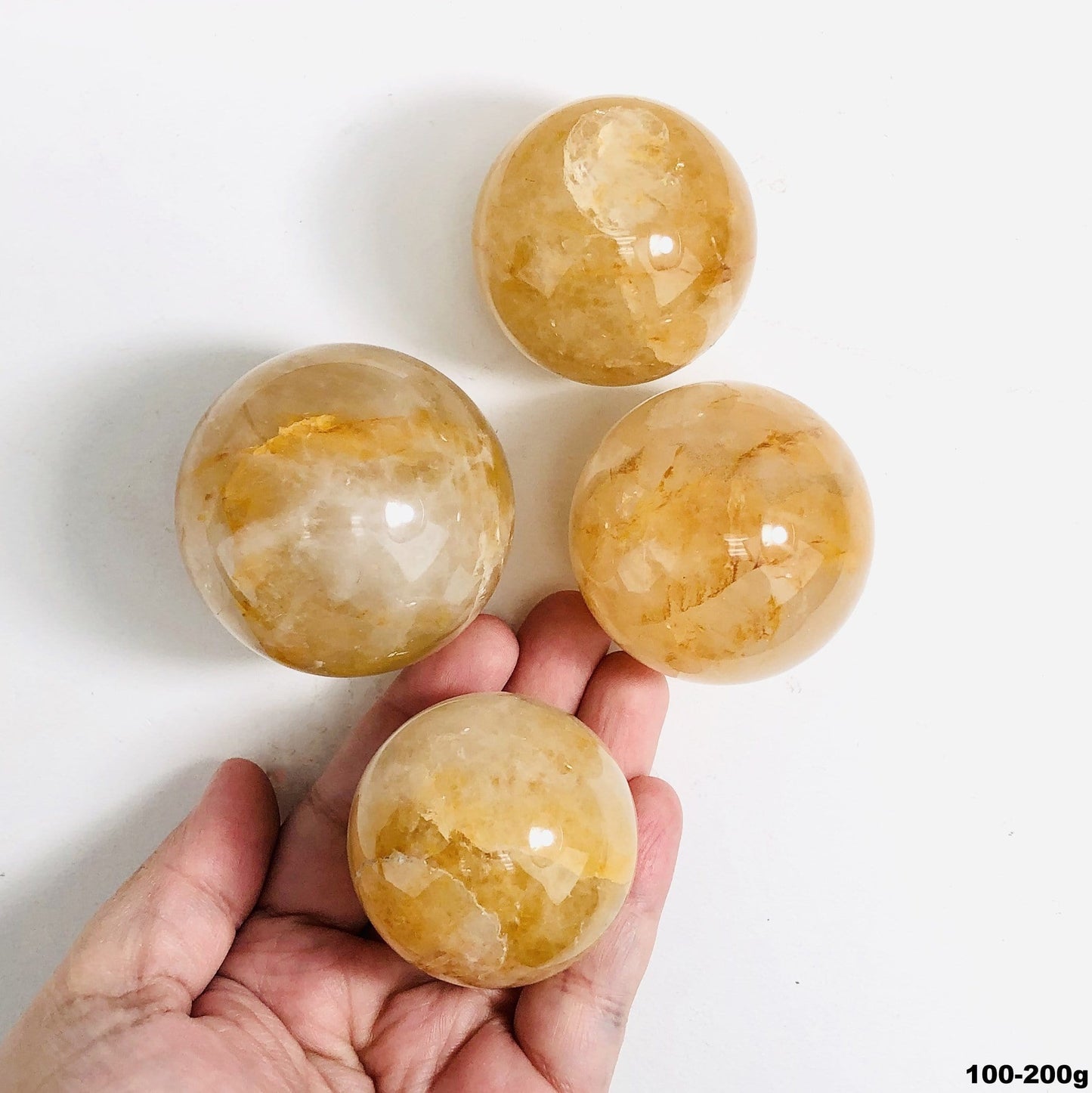 100-200g golden healer polished spheres on white background