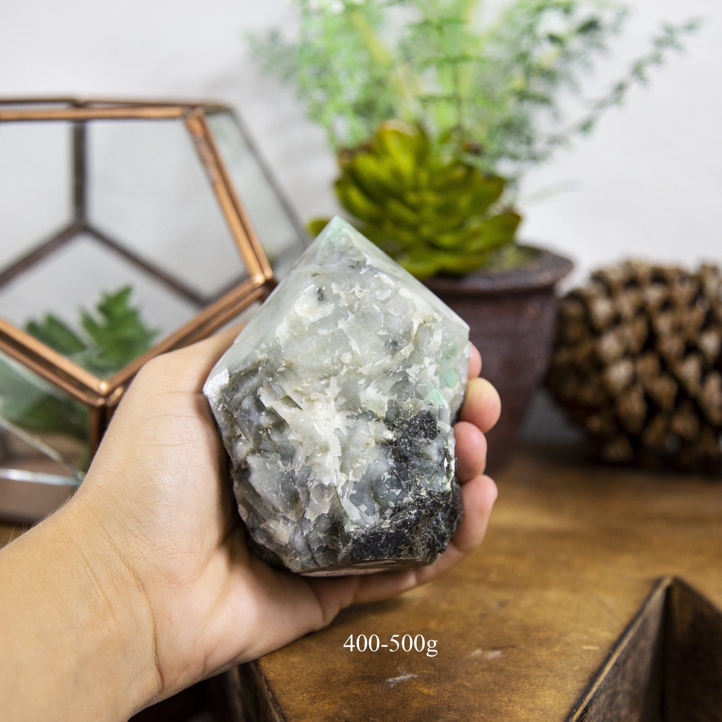 Semi Polished point Emerald Stone in hand showing the weight of 400 to 500g on white background