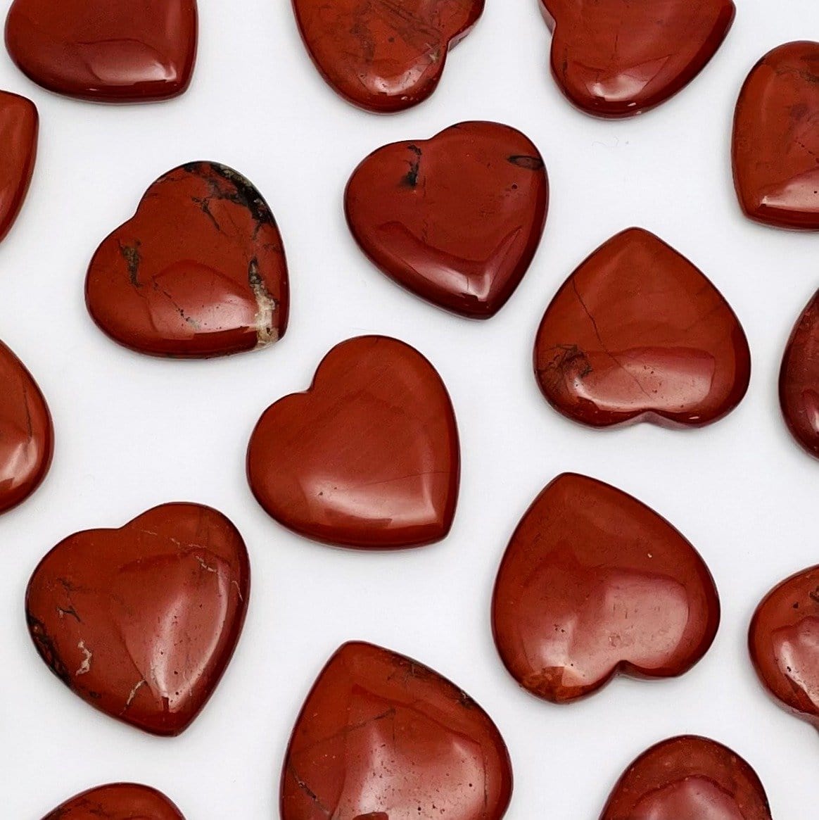 Red Jasper Heart Shaped Stones scattered across white background