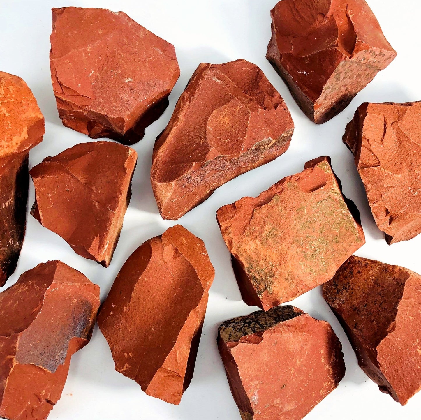 11 Red Jasper Rough Stones scattered on white background