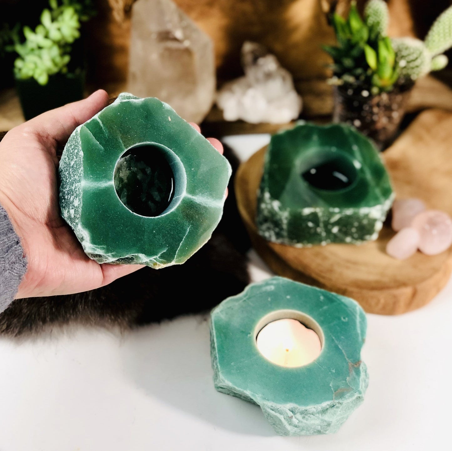 Hand holding up rough stone candle holder with 2 others in the background with decorations