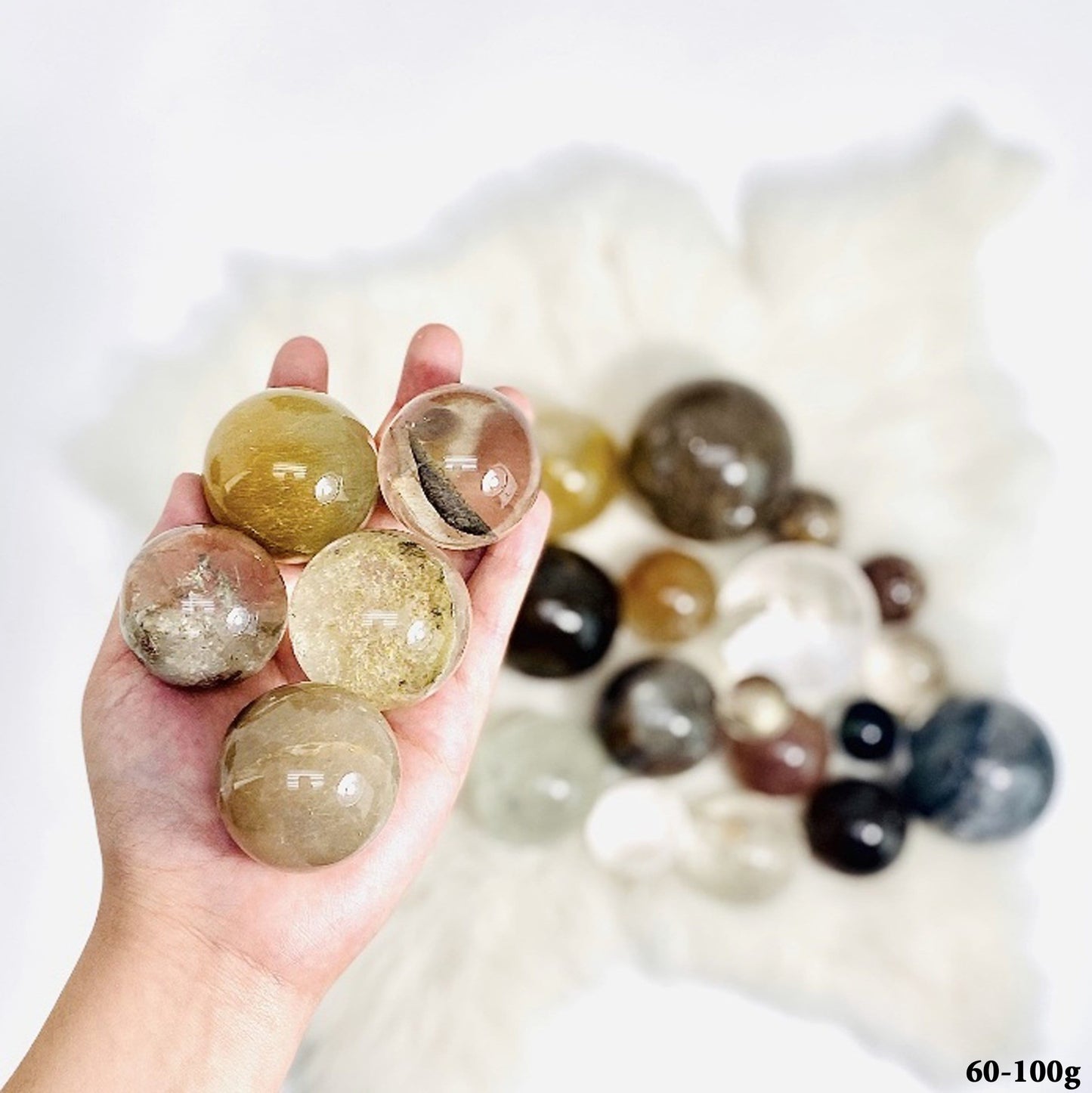 Assorted Quartz Spheres, between 60-100g, displayed in hand 