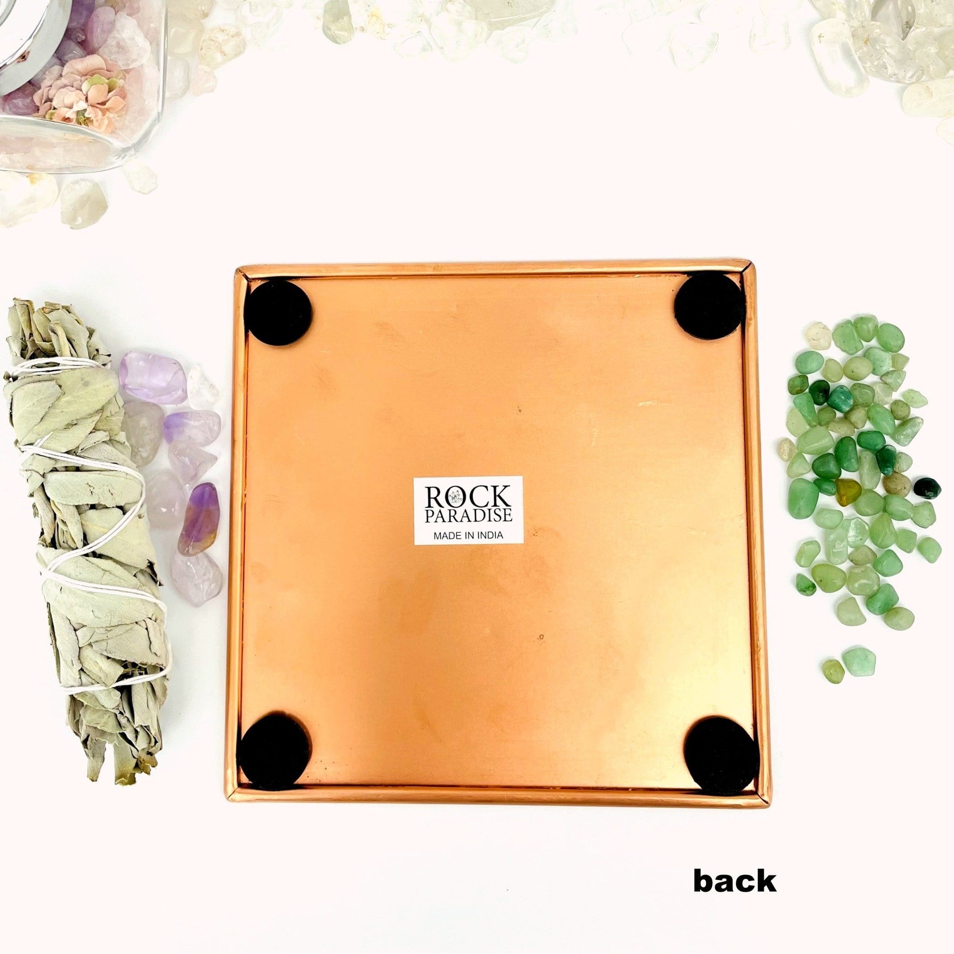 back side of copper square plate showing 4 black felt pads on the corner 