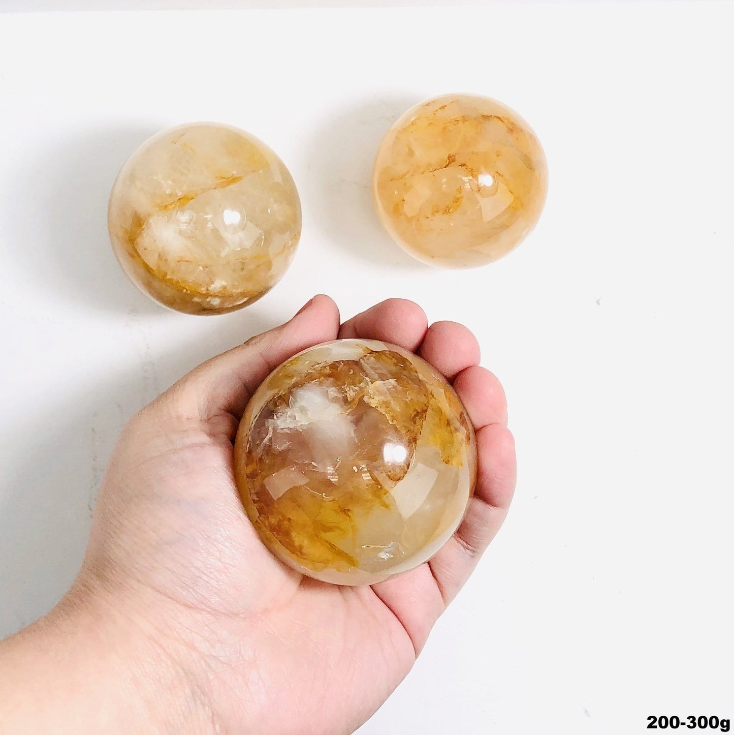 200-300g golden healer polished spheres on white background