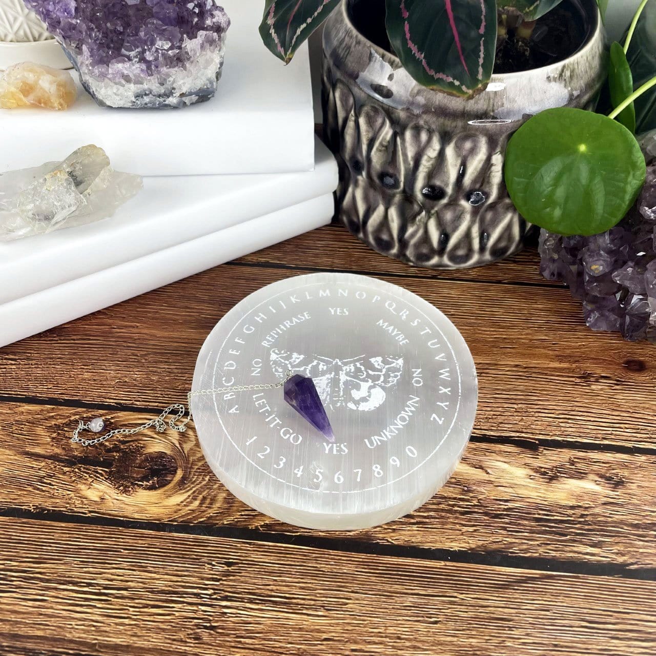 selenite moth pendulum board engraved charging plate on display with pendulums 