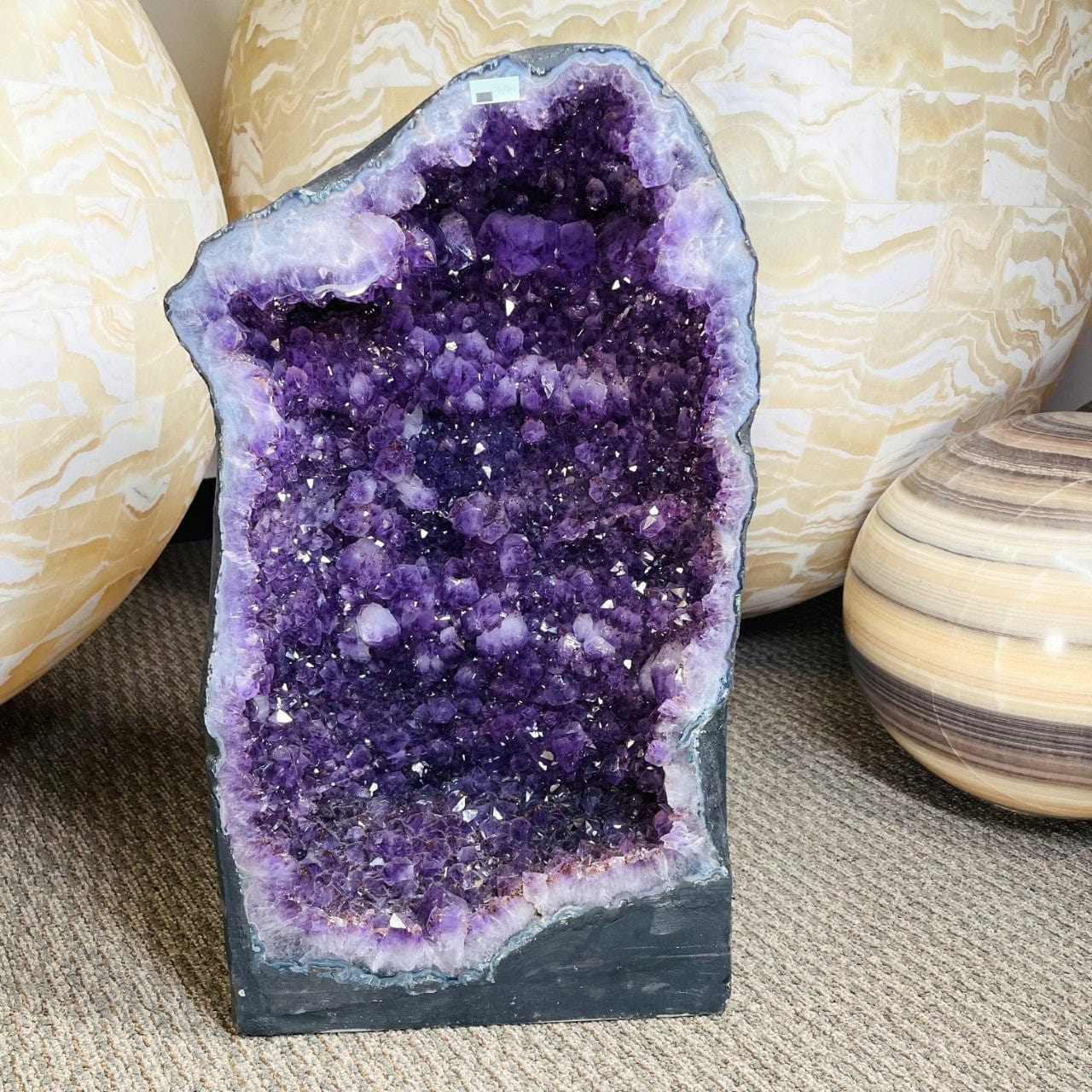 Amethyst Crystal Cathedral Geode  on display with large spheres behind