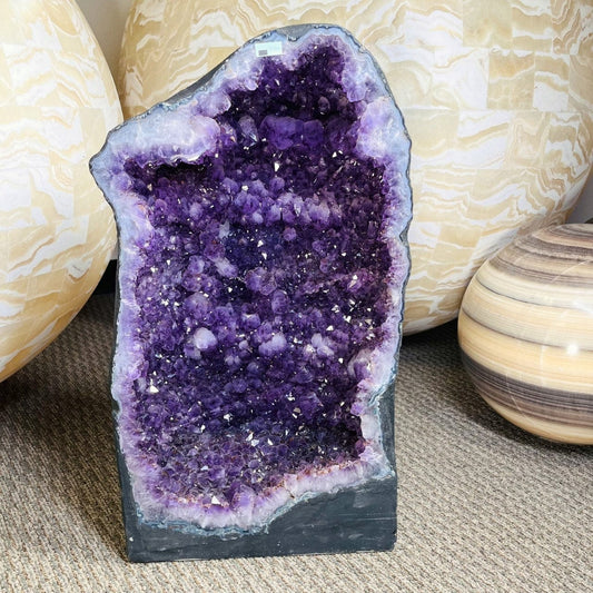 Amethyst Crystal Cathedral Geode  on display with large spheres behind