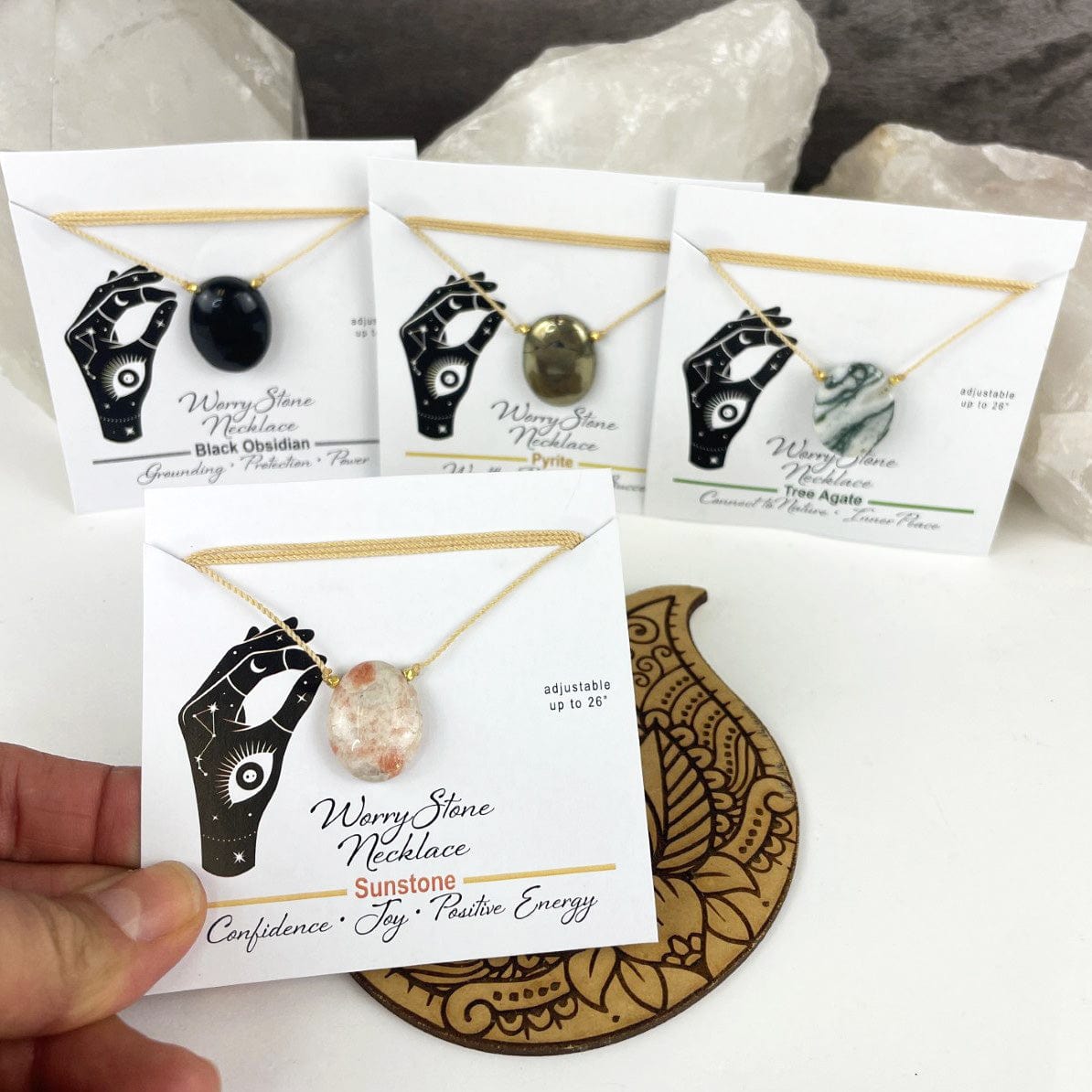 worrystone necklaces on their display cards and the sunstone in a hand