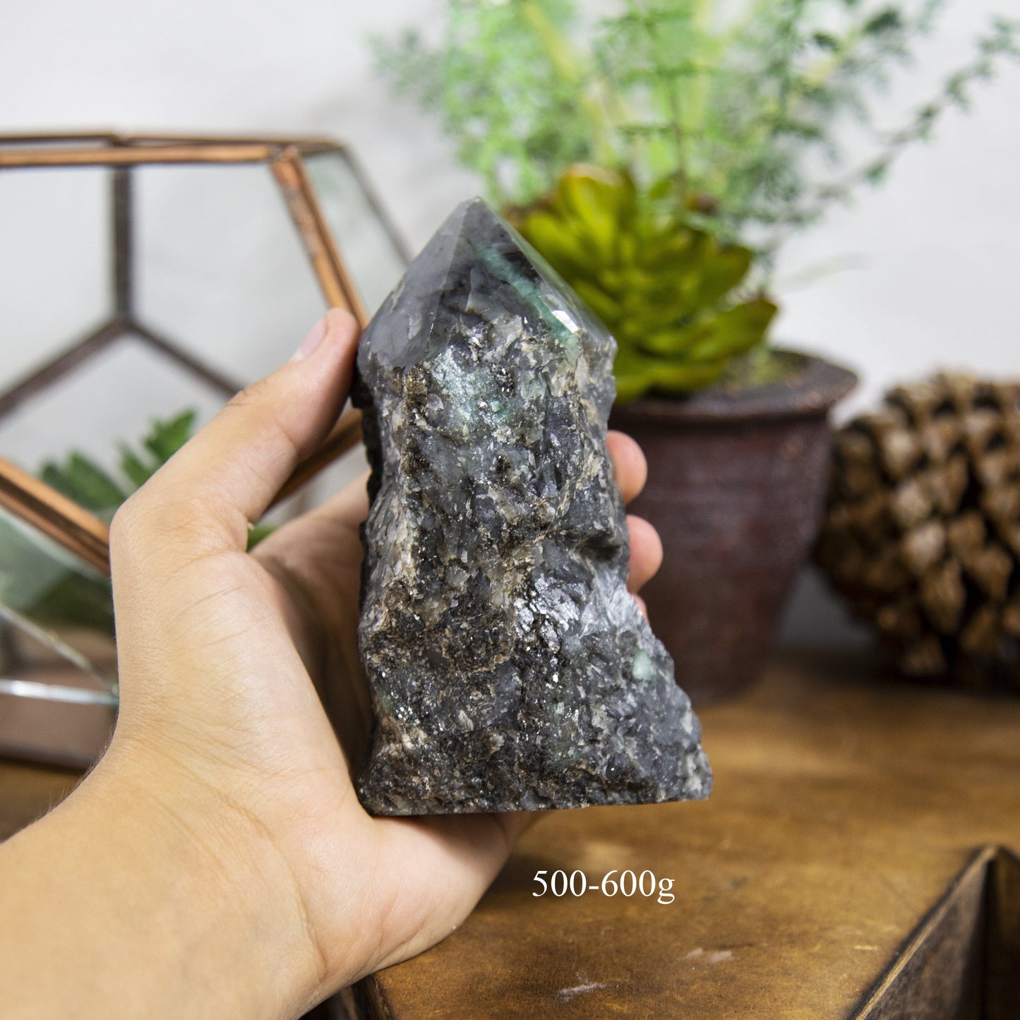 Semi Polished point Emerald Stone in hand showing the weight of 500 to 600g on white background