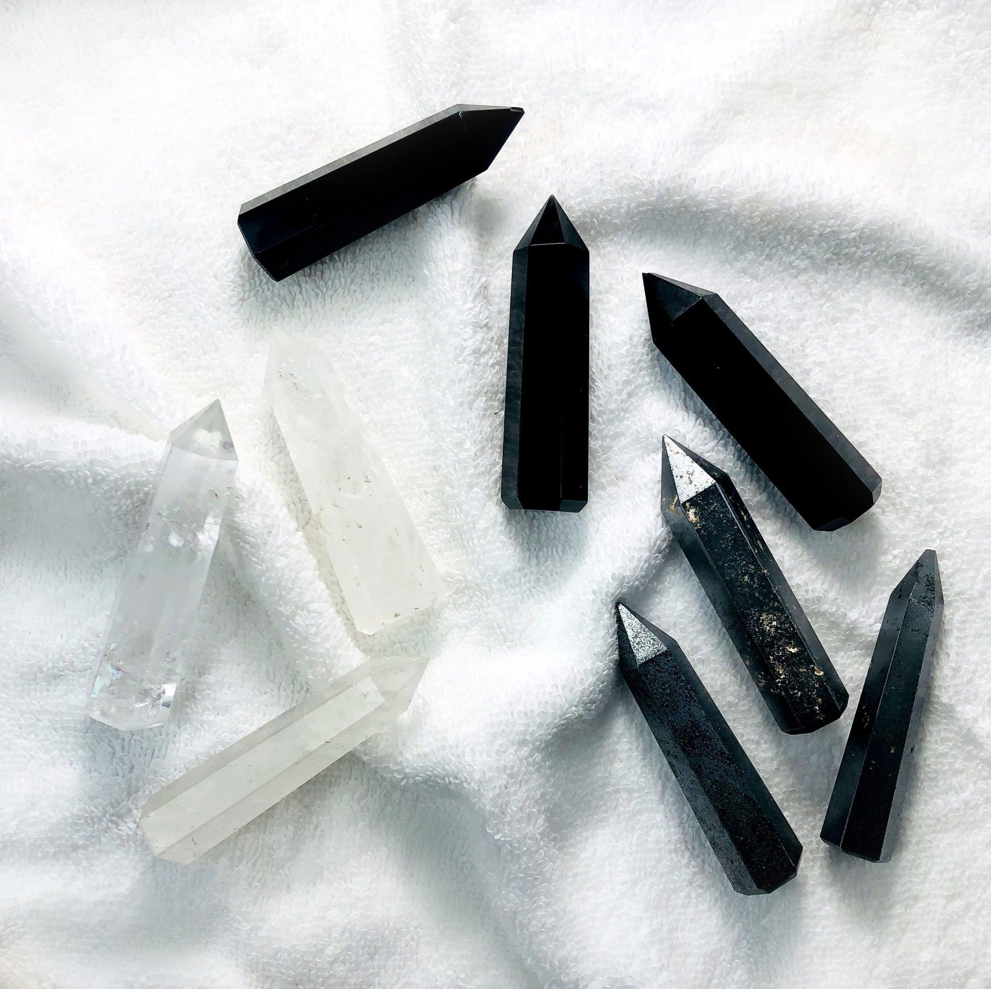 3 different colored Gemstone Pencil Polished Points displayed on white terry cloth