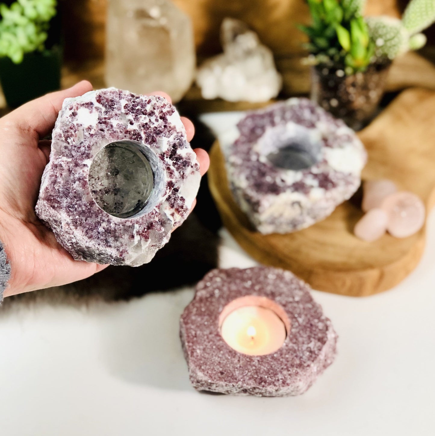 Hand holding up rough stone candle holder with 2 others in the background with decorations