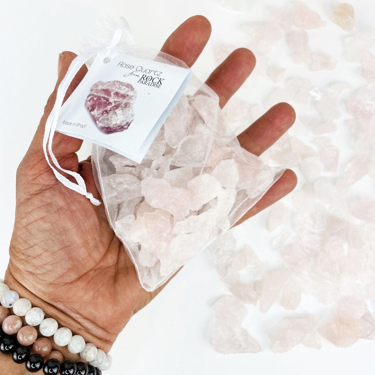 rough rose quartz in hand for size reference tied and tagged in an organza bag