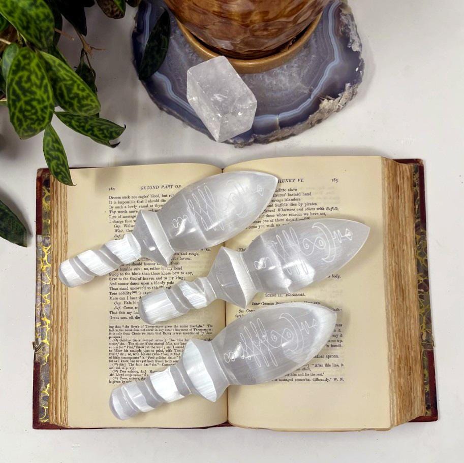 overhead view of selenite twisted handle knives with unalome engraving on display for engraving details and possible variations