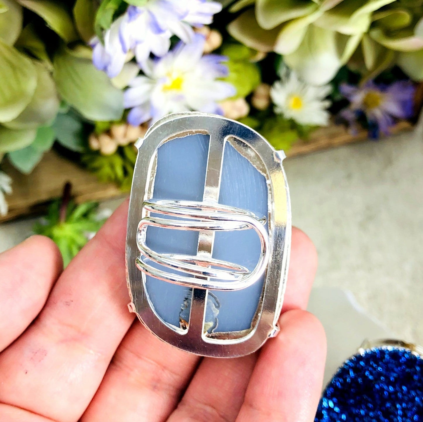 ring displayed in hand to show back of the ring and adjustable band