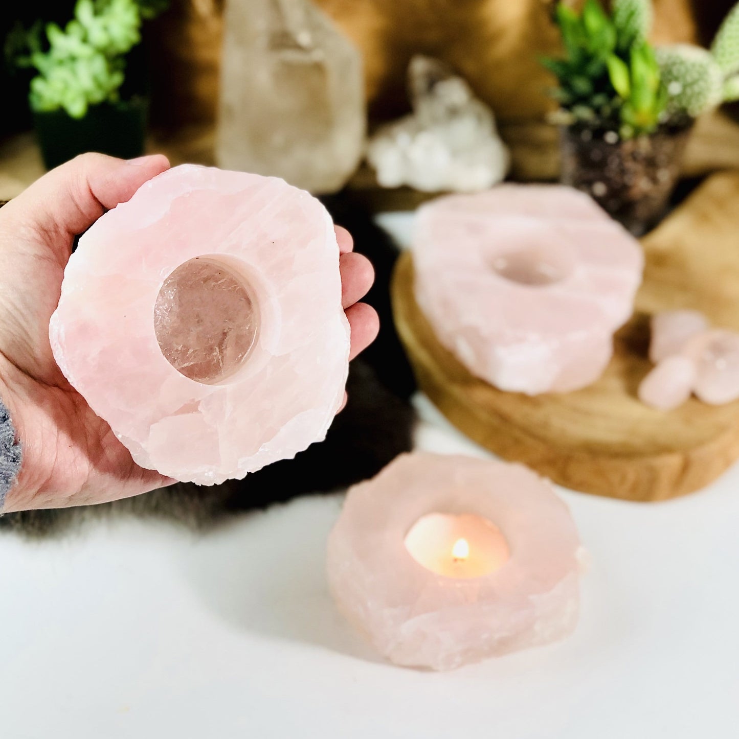 Hand holding up rough stone candle holder with 2 others in the background with decorations