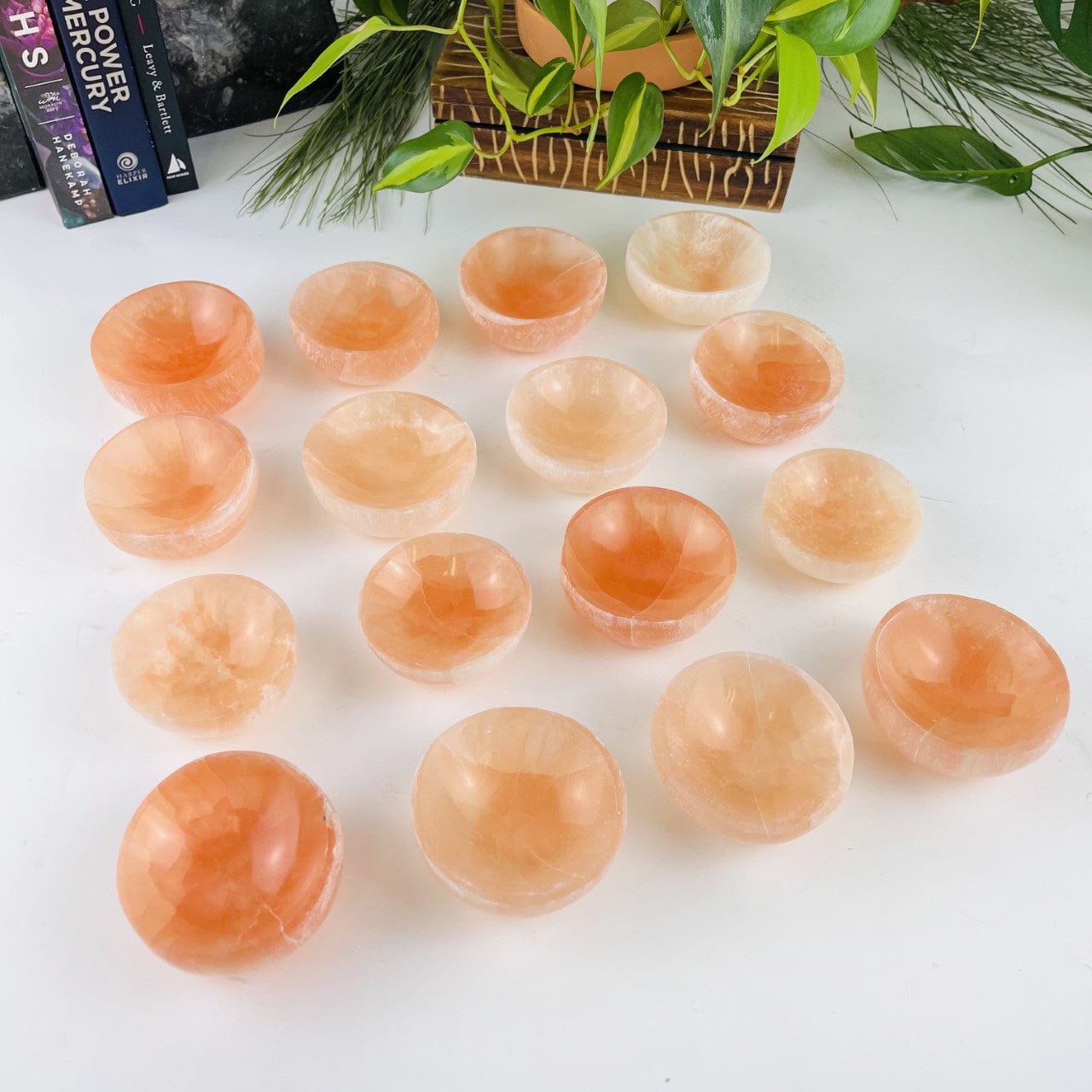 16 orange selenite bowls on a table showing color variations