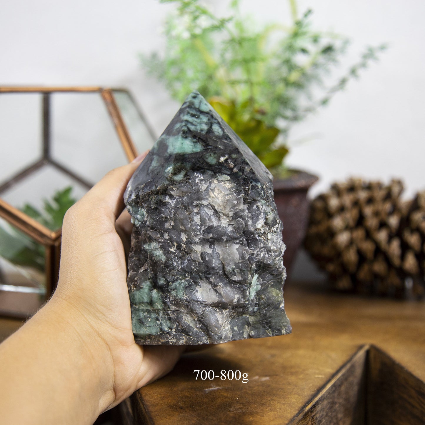Semi Polished point Emerald Stone in hand showing the weight of 700 to 800g on white background