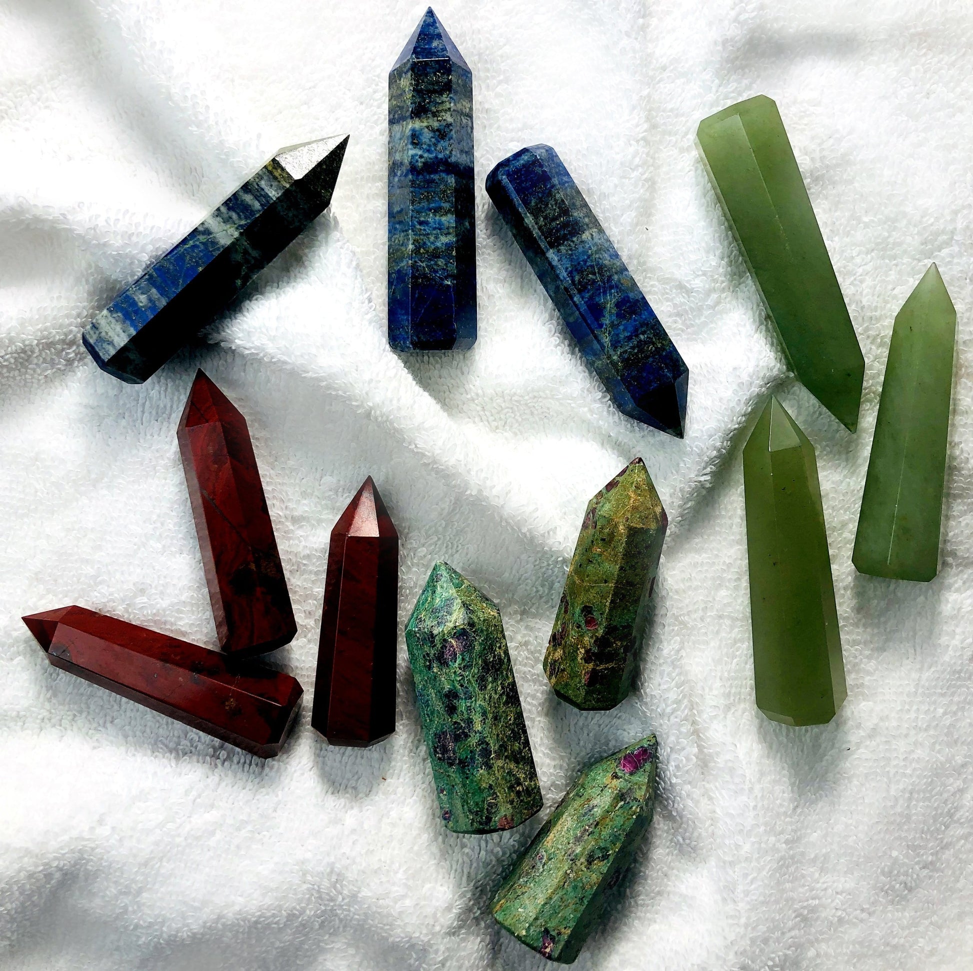 4 different colored Gemstone Pencil Polished Points displayed on white terry cloth