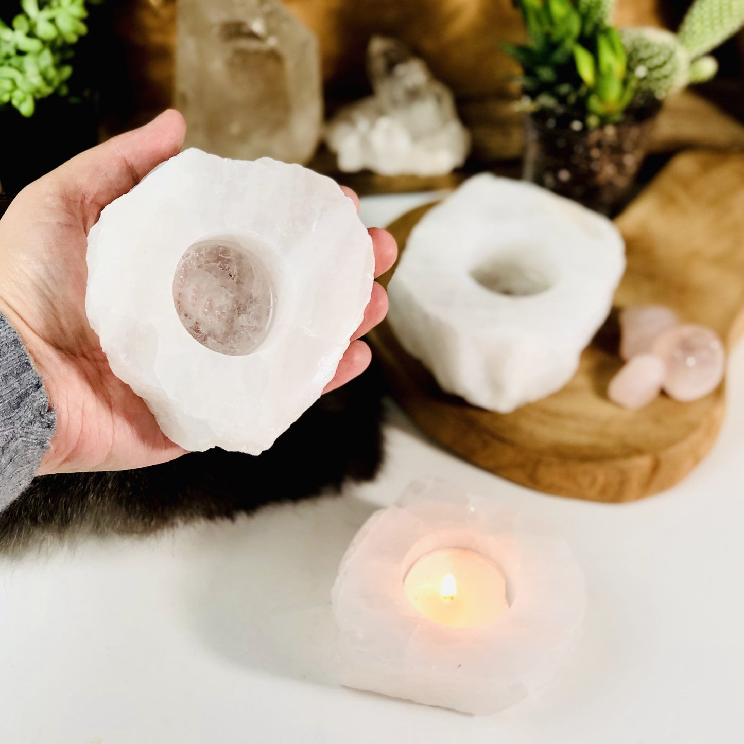 Hand holding up rough stone candle holder with 2 others in the background with decorations