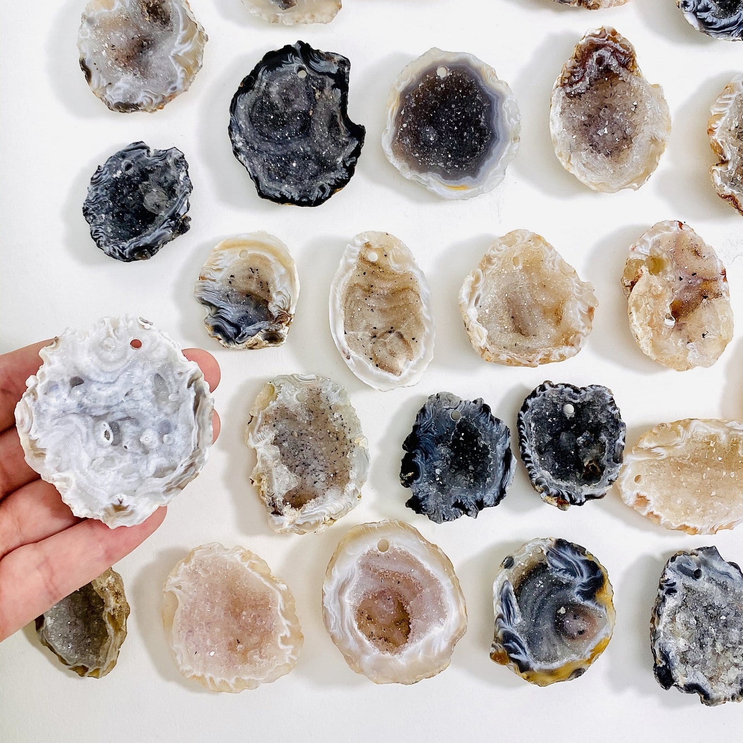 hand holding up drilled druzy geode with others in the background