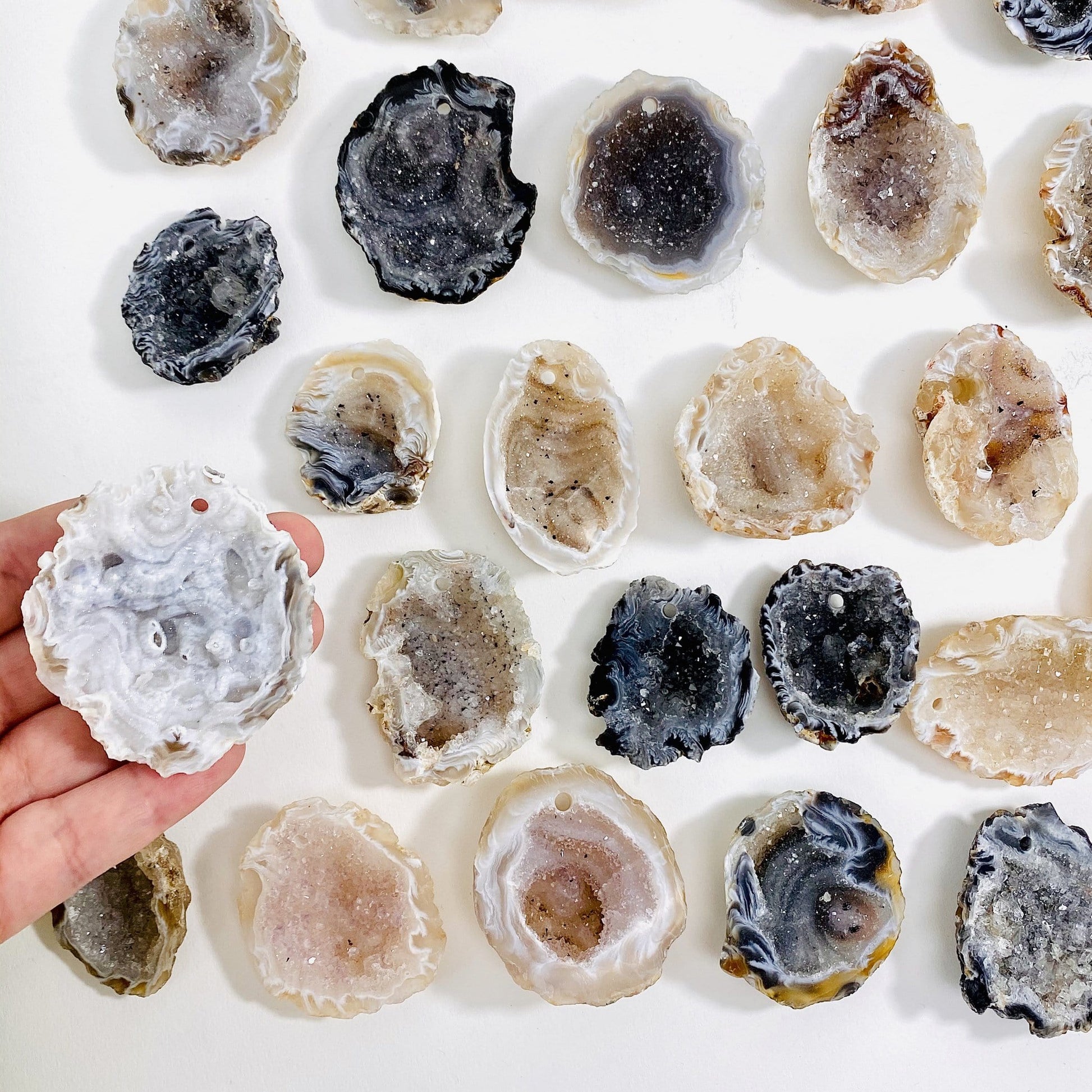 hand holding up drilled druzy geode with others in the background