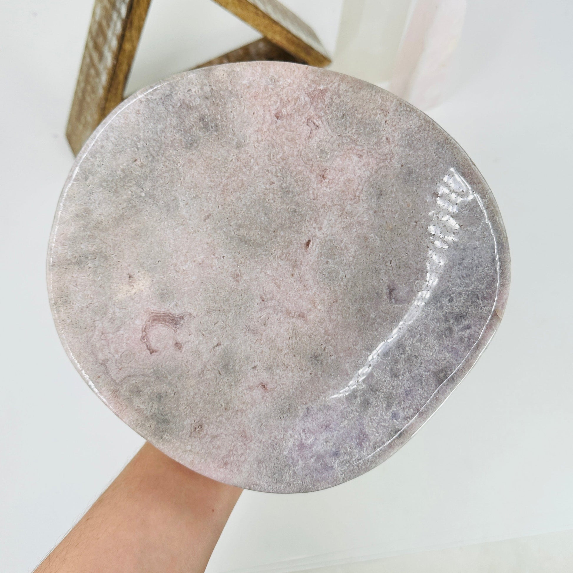 hand holding up pink amethyst bowl with decorations in the background