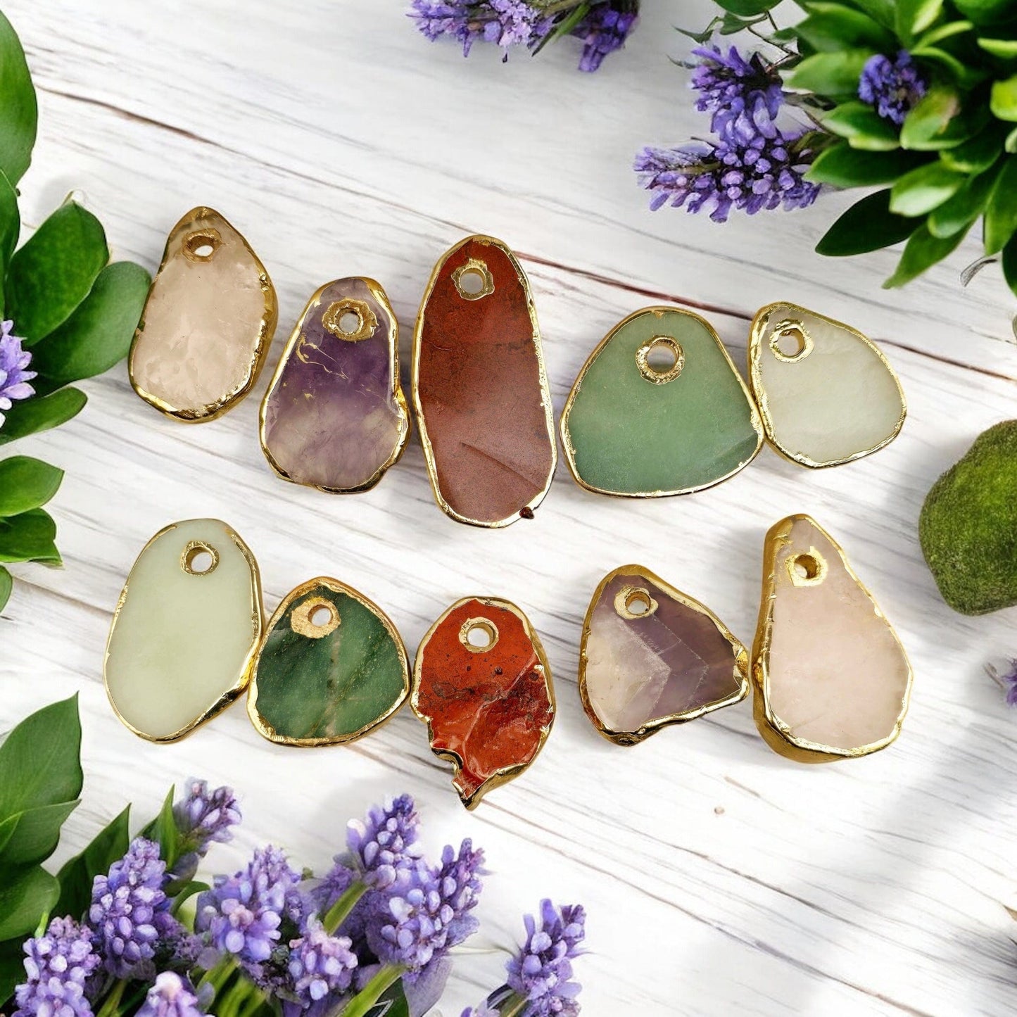 10 different assorted crystal pendants on white wooden background with succulents and lavender flowers