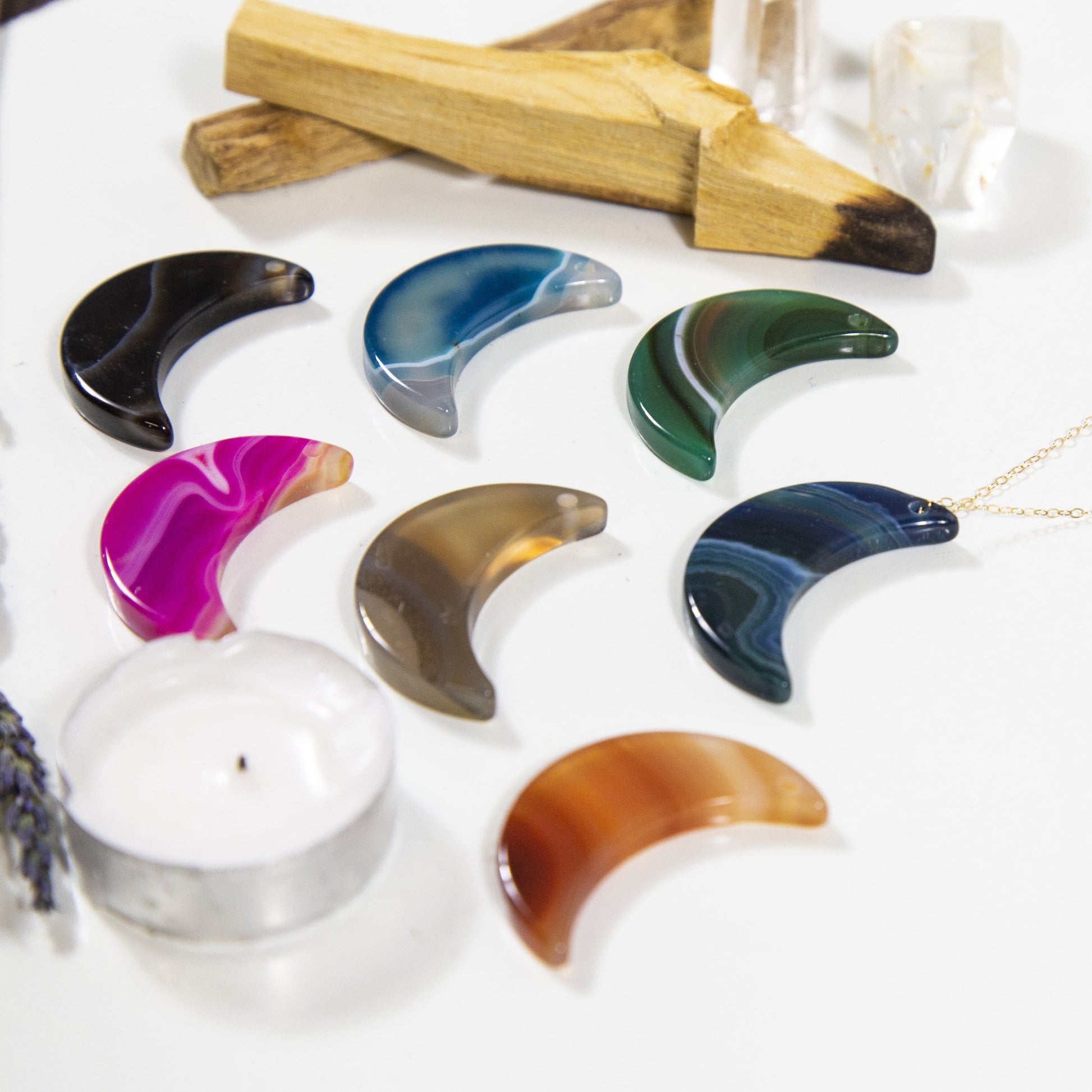 Close Up of Assorted Color Drilled Half Moon Agate With Necklace on White Background.