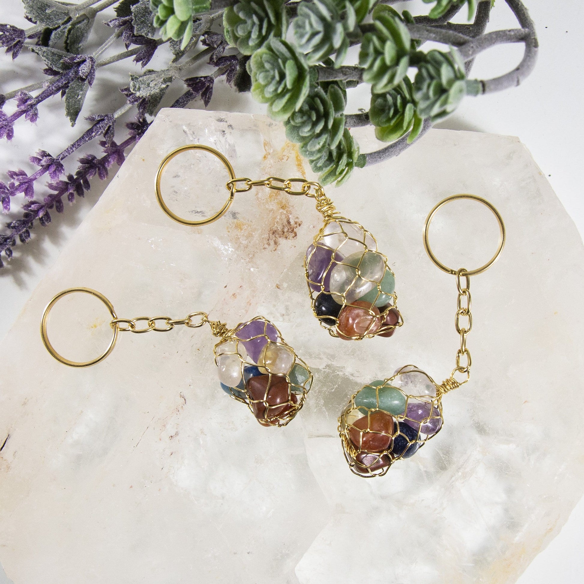 three seven stone chakra tumbled stone gold keychains on display