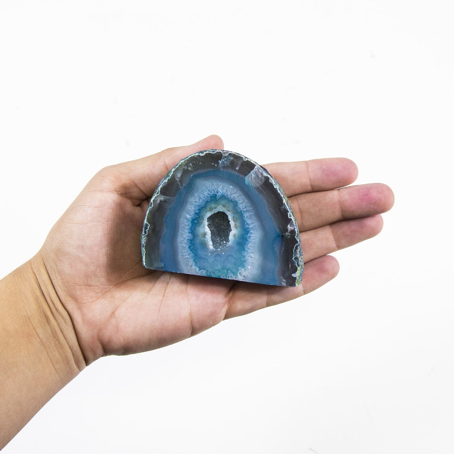 One Agate Half Geode Druzy in a hand with a white background.