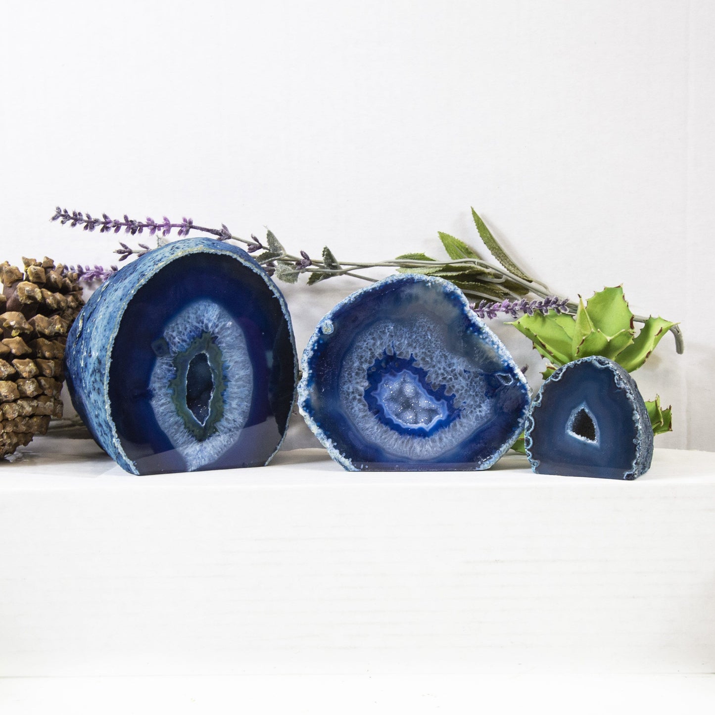 Three front facing blue Agate Half Geode Druzy in an alter with a white background displaying size, pattern and color variation.