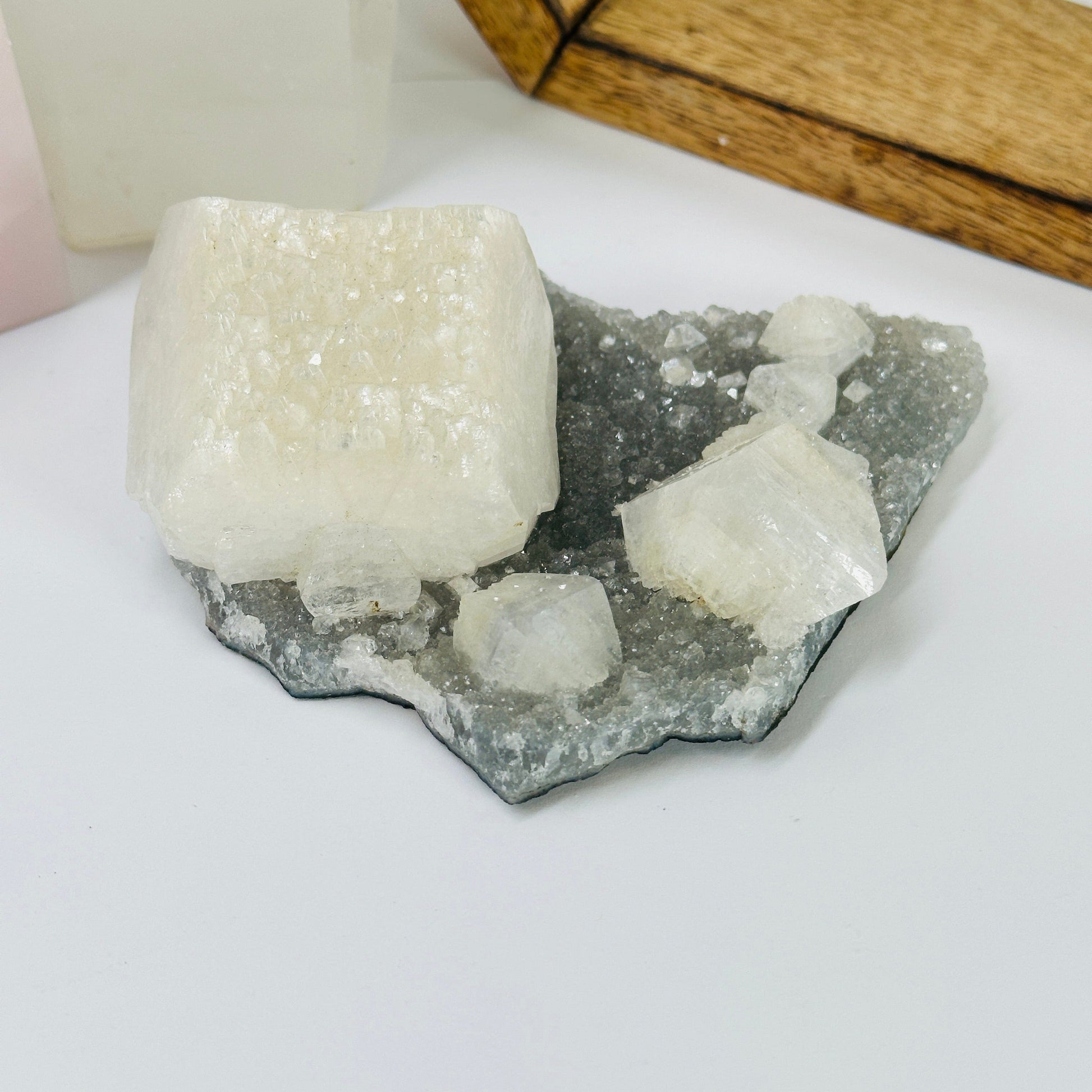 zeolite apophyllite on matrix with decorations in the background
