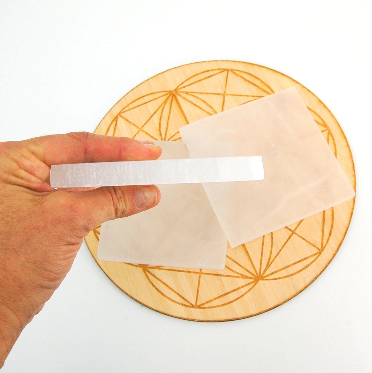 side view of square selenite charging plate in hand for thickness