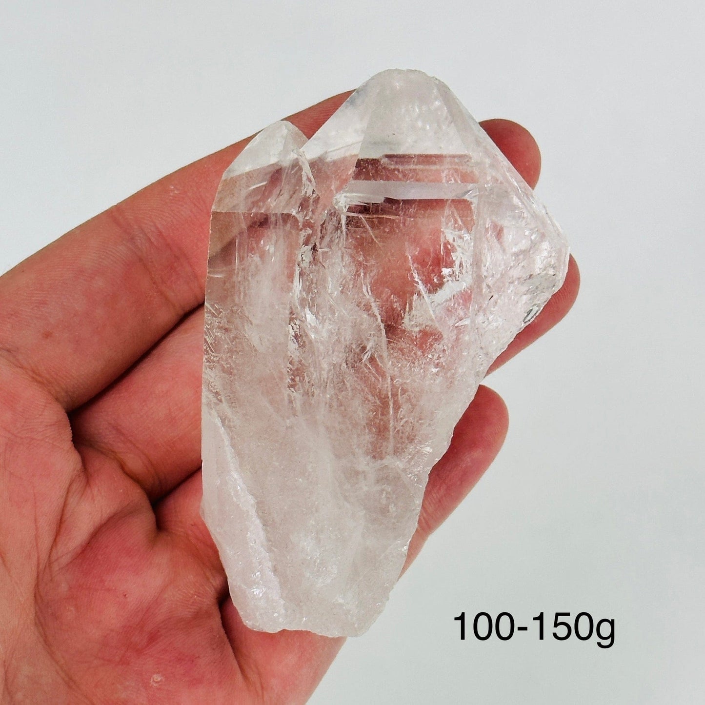 hand holding up crystal quartz point on white background