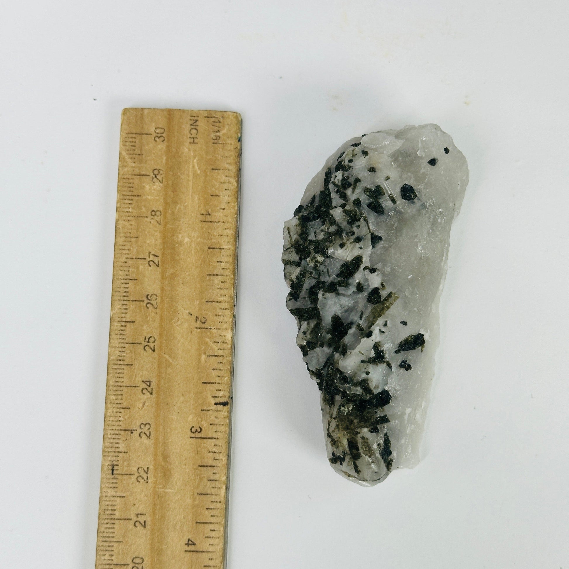 epidote on matrix next to a ruler for size reference