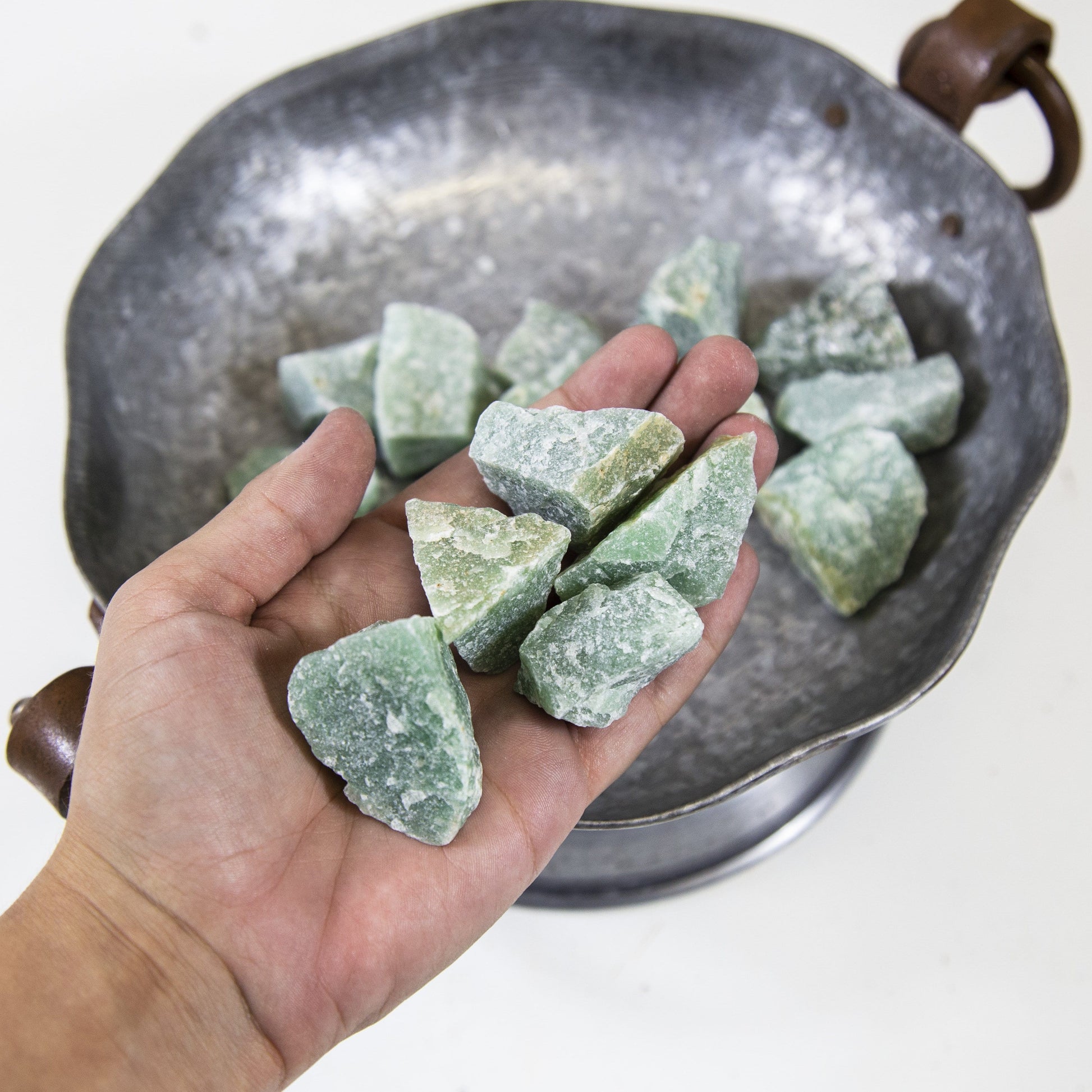 rough chunks of green quartz pieces in hand for size reference