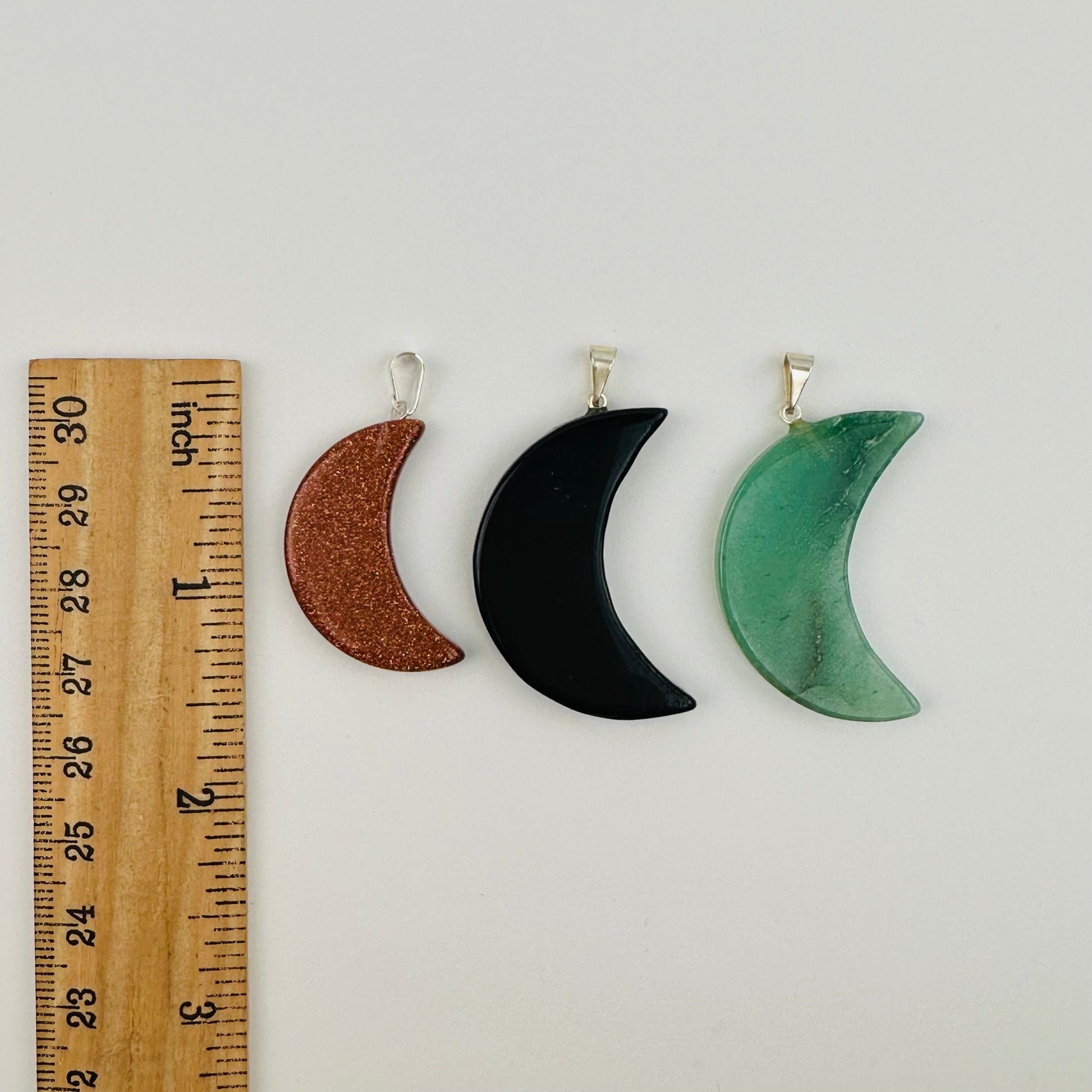 pendants next to a ruler for size reference 
