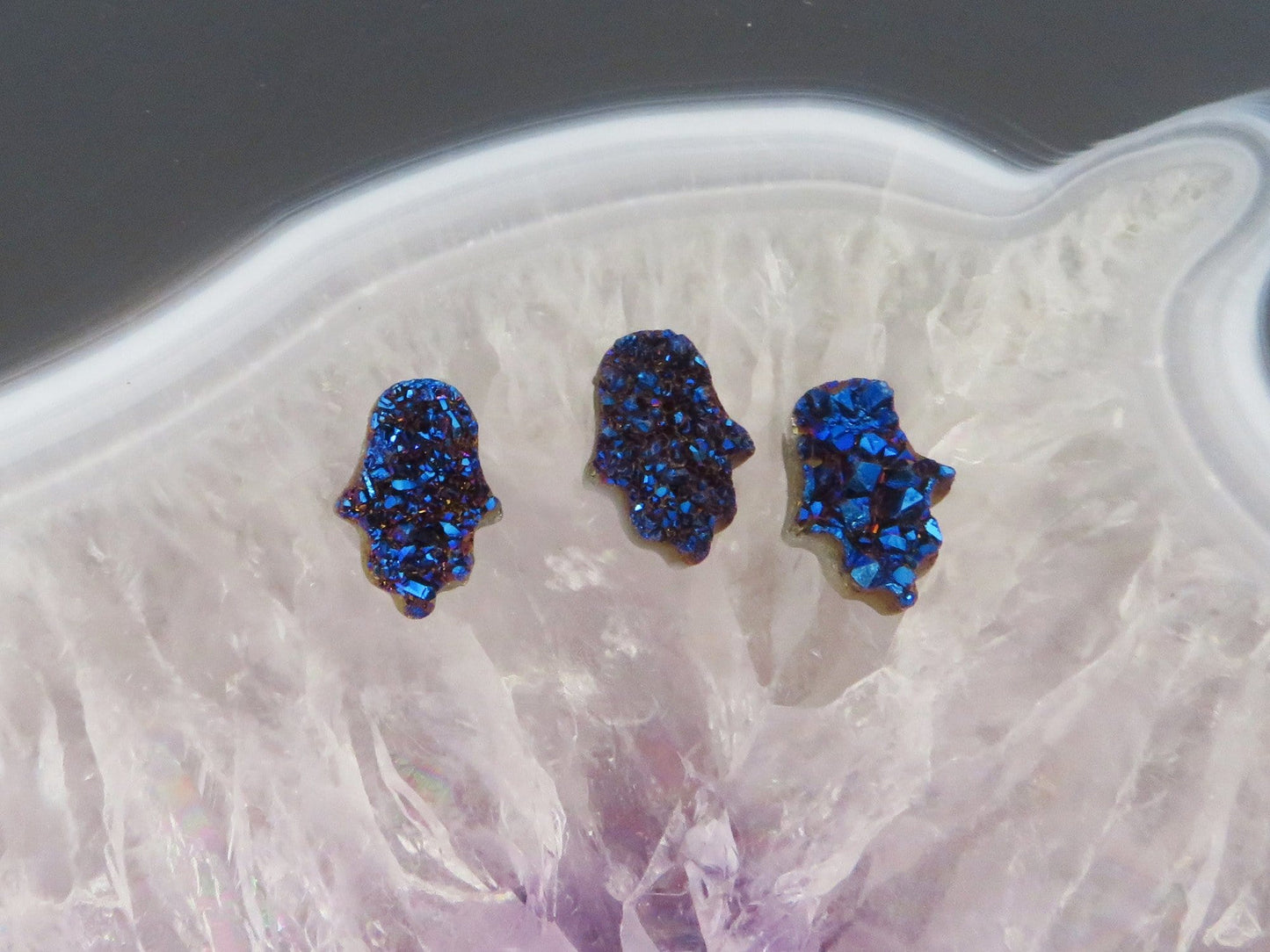 head drilled hamsa bead titanium druzy in assorted color shown against light backgrounds